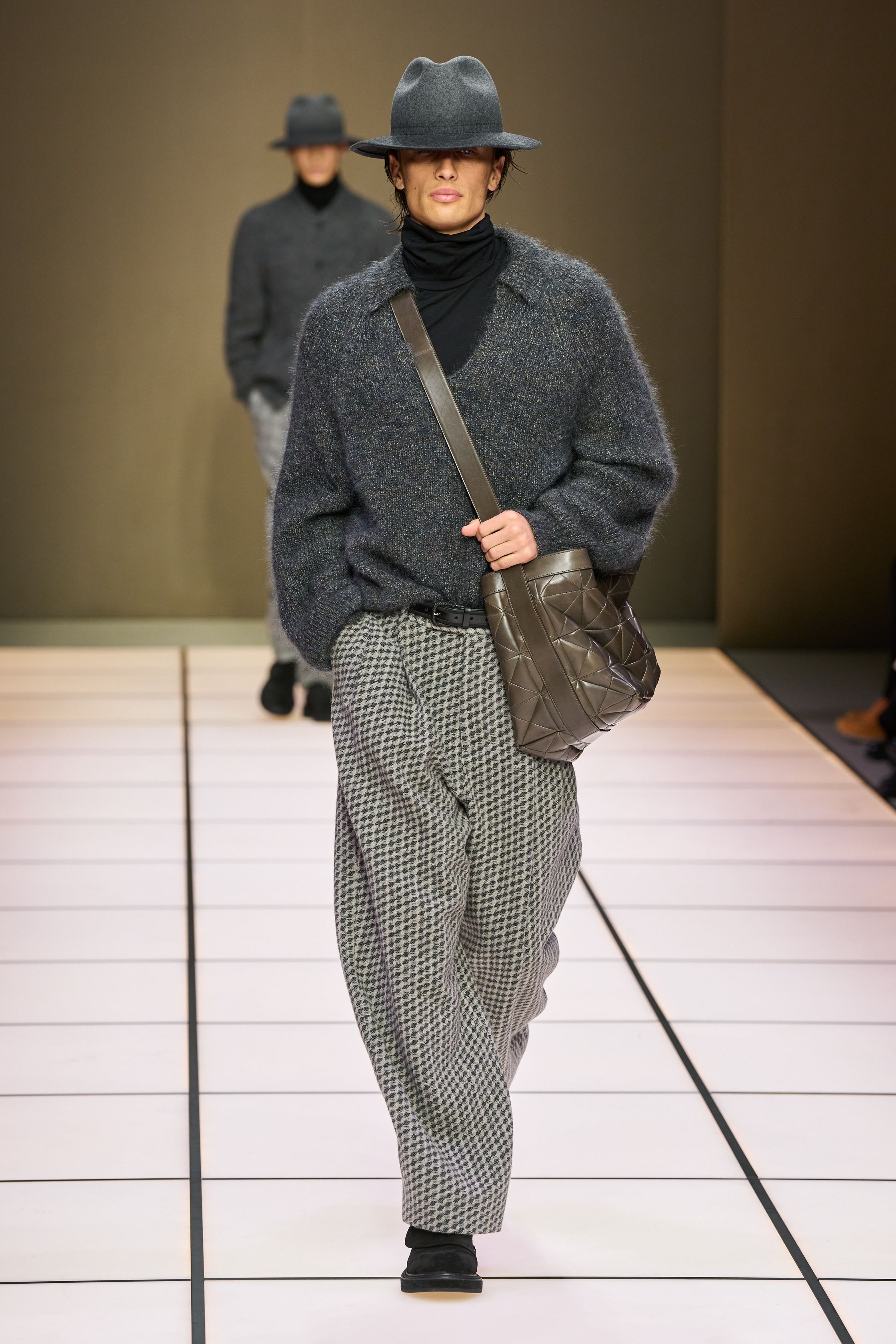 Giorgio Armani 26FW 男装回归品牌最本质的语言：流动、克制与永恒。柔软大衣、宽松长裤、针织与轻结构西装在灰、驼、米与墨绿中缓慢展开，强调身体与面料之间的自然关系。系列几乎不依赖任何戏剧化装饰，却通过比例、步伐与质感建立权威感，是对“真正优雅无需证明”的再次确认，也是一种对快节奏时尚的温和抵抗-顽石频道趋势研究